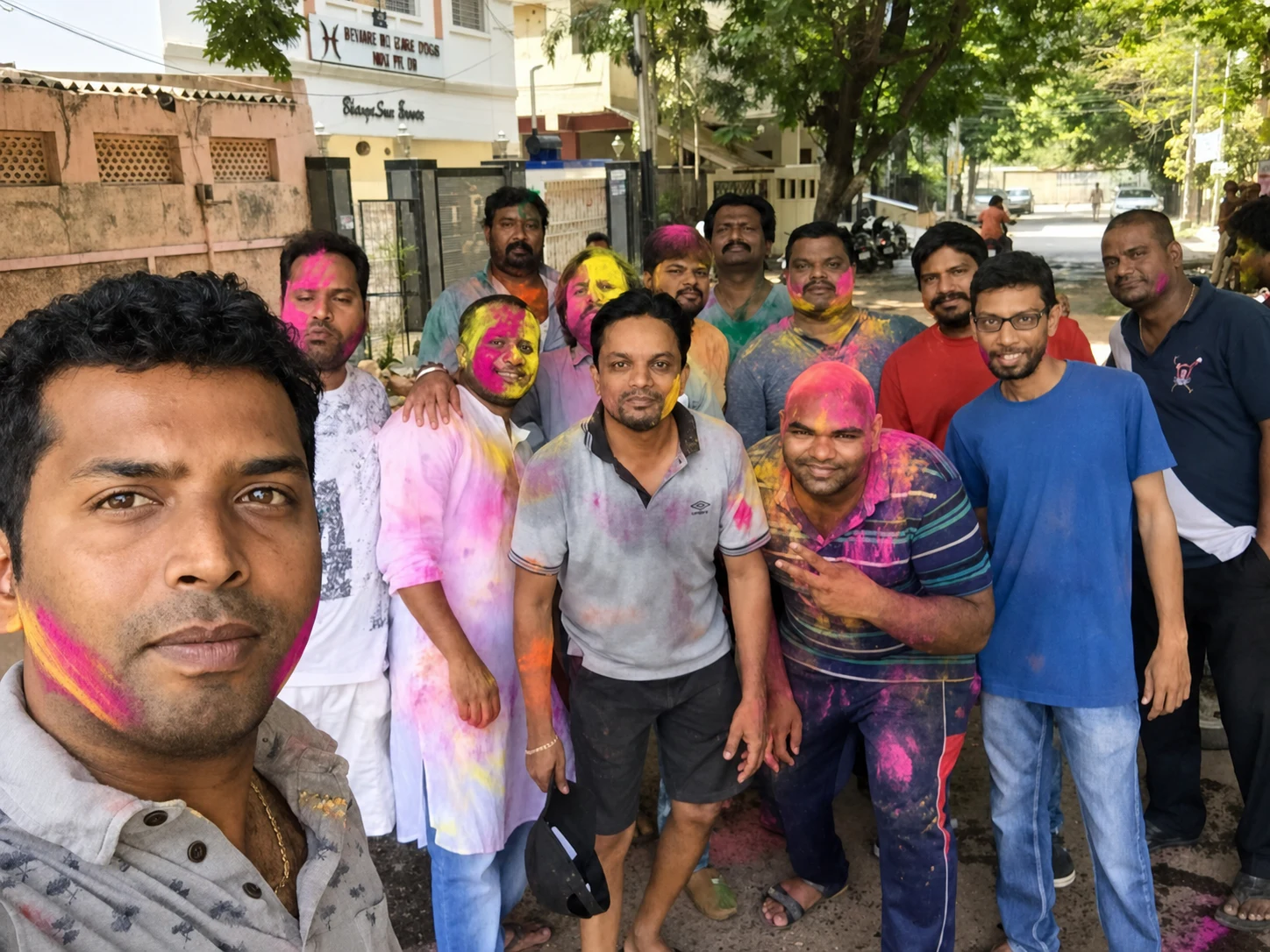 Friends covered in Holi colours posing together on a neighbourhood lane